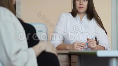 一位穿着黑色T恤的年轻漂亮孕妇正在和一位穿着白色外套的年轻女医生谈话。